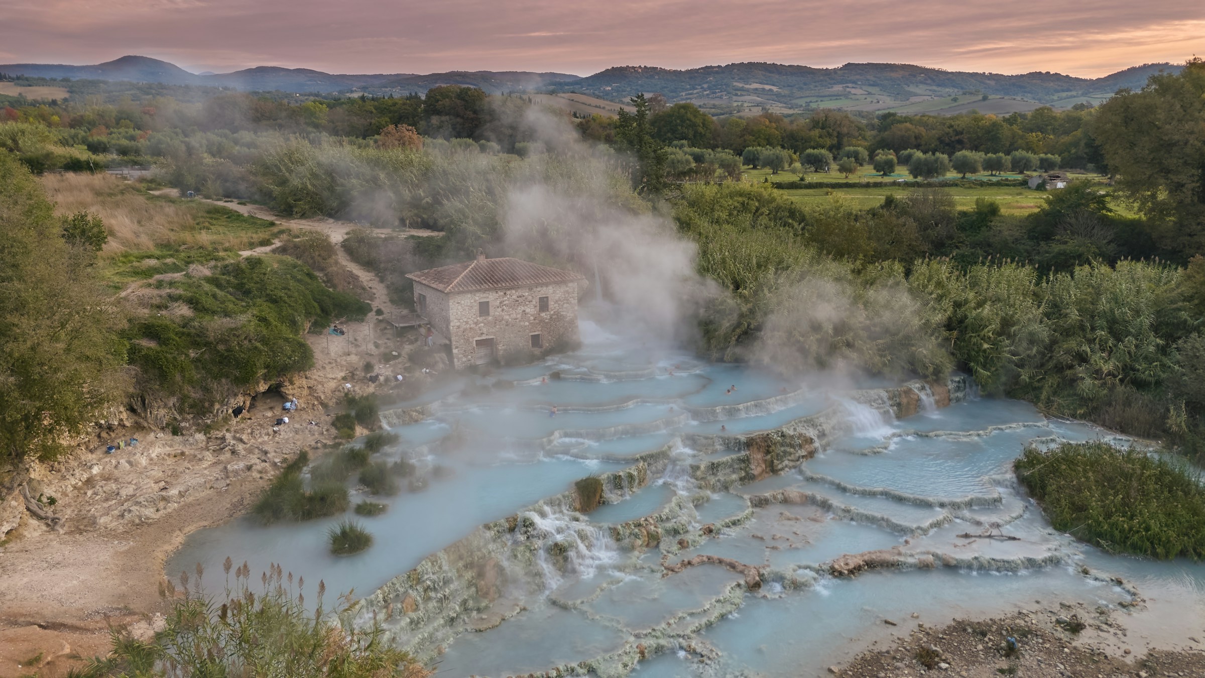 Morning light and steam over the terraced travertine pools at Saturnia, below the old mill